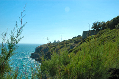 Picture of cliffs on a coastline in brilliant sunshine, a lighthouse in the distance