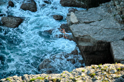 Picture of a young man jumping off a cliff into the sea