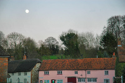 Picture of the moon over a pink row of cottages