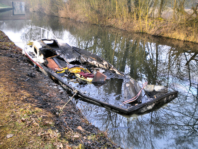 Picture of a burned out small sports boat on a canal