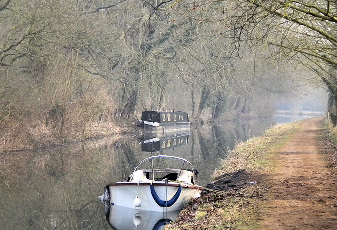 Picture of a burned out small sports boat, another canal boat in the background